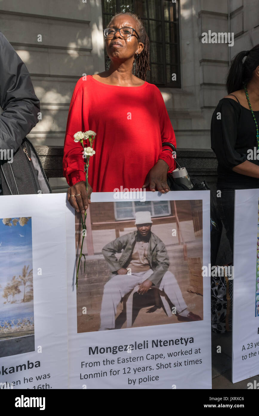 London, UK. 16th August 2017. A woman holds a sunflower and a poster of one of the miners who was killed at the protest vigil outside the South African High Commission in Trafalgar Square on the 5th anniversary of the massacre when 34 striking miners were shot dead by South African police at Lonmin's Marikana platinum mine. Credit: Peter Marshall/Alamy Live News Stock Photo