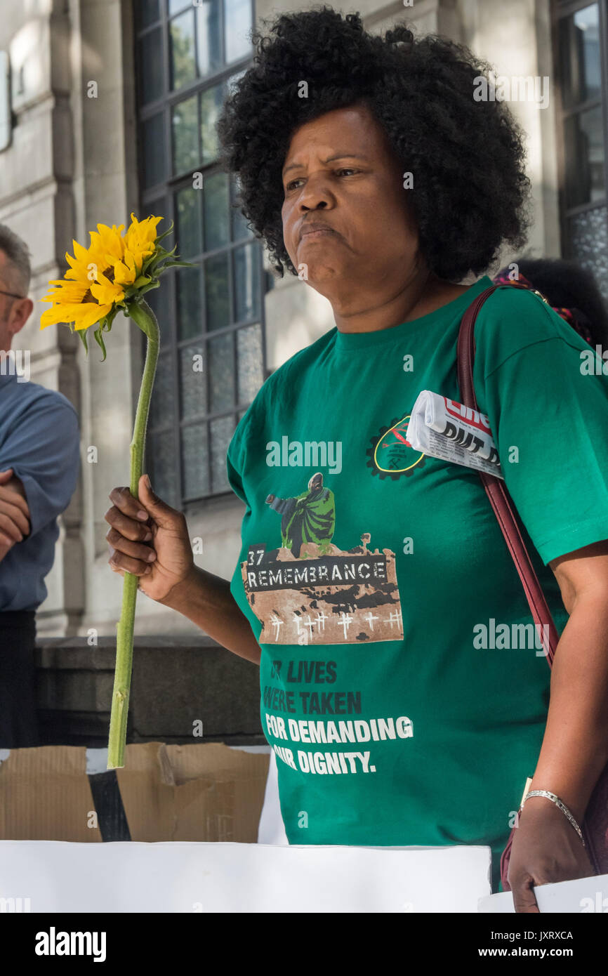London, UK. 16th August 2017. Thumeka Magwangqana holds a sunflower and poster at the protest vigil outside the South African High Commission in Trafalgar Square on the 5th anniversary of the massacre when 34 striking miners were shot dead by South African police at Lonmin's Marikana platinum mine. Credit: Peter Marshall/Alamy Live News Stock Photo