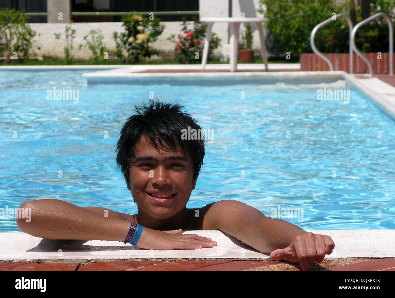Smiling boy lying on side of swimming pool Stock Photo