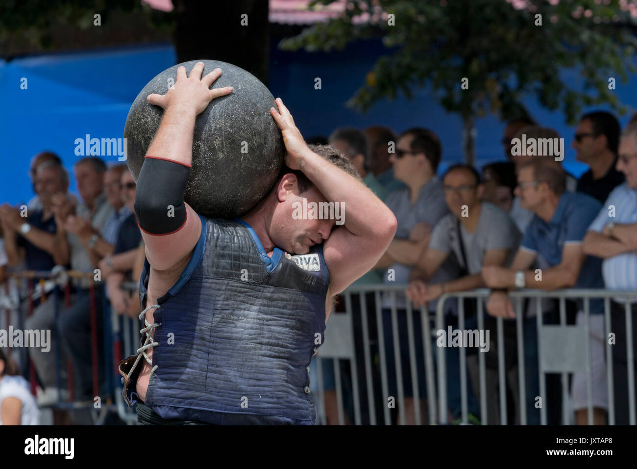 Huge round stone on the shoulders of a basque stone lifter (harrijasotzaile) in a competition. Stock Photo