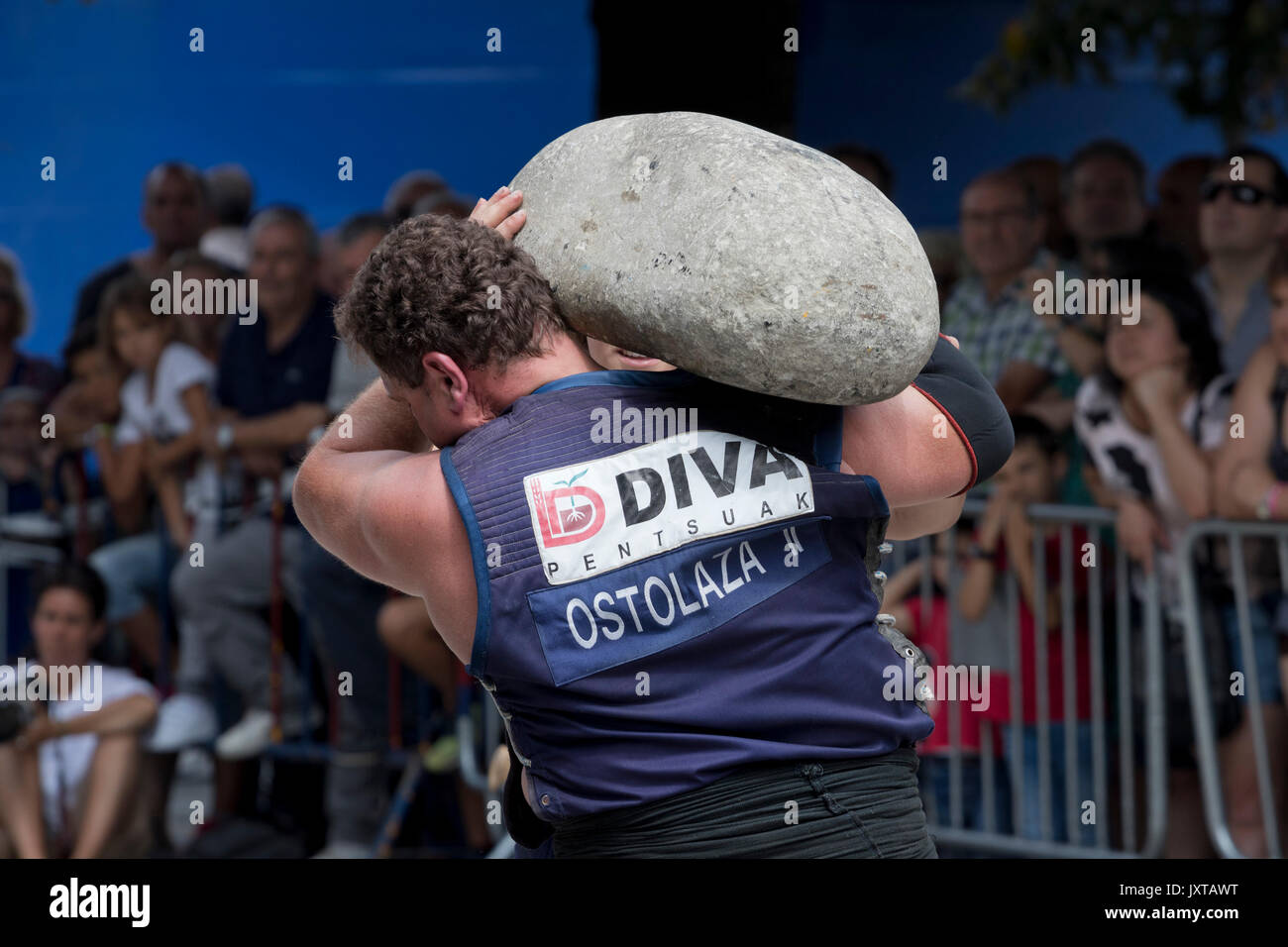 Basque stone lifter (harrijasotzaile) lifting a huge granite stone in a competition. Stock Photo