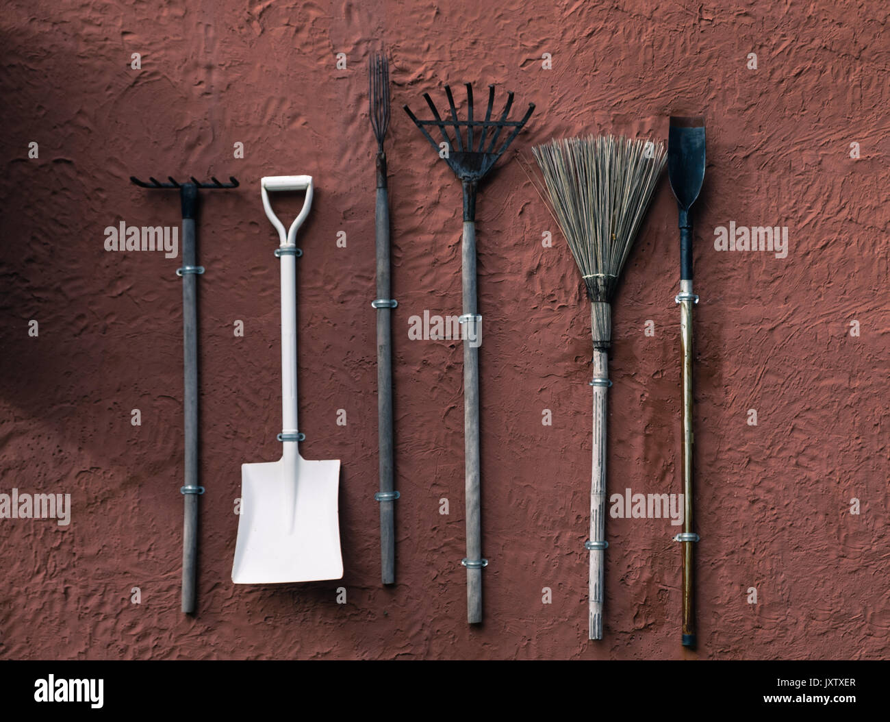 Broom, shovel, rake,spade hang on orange cement wall,Garden equipment