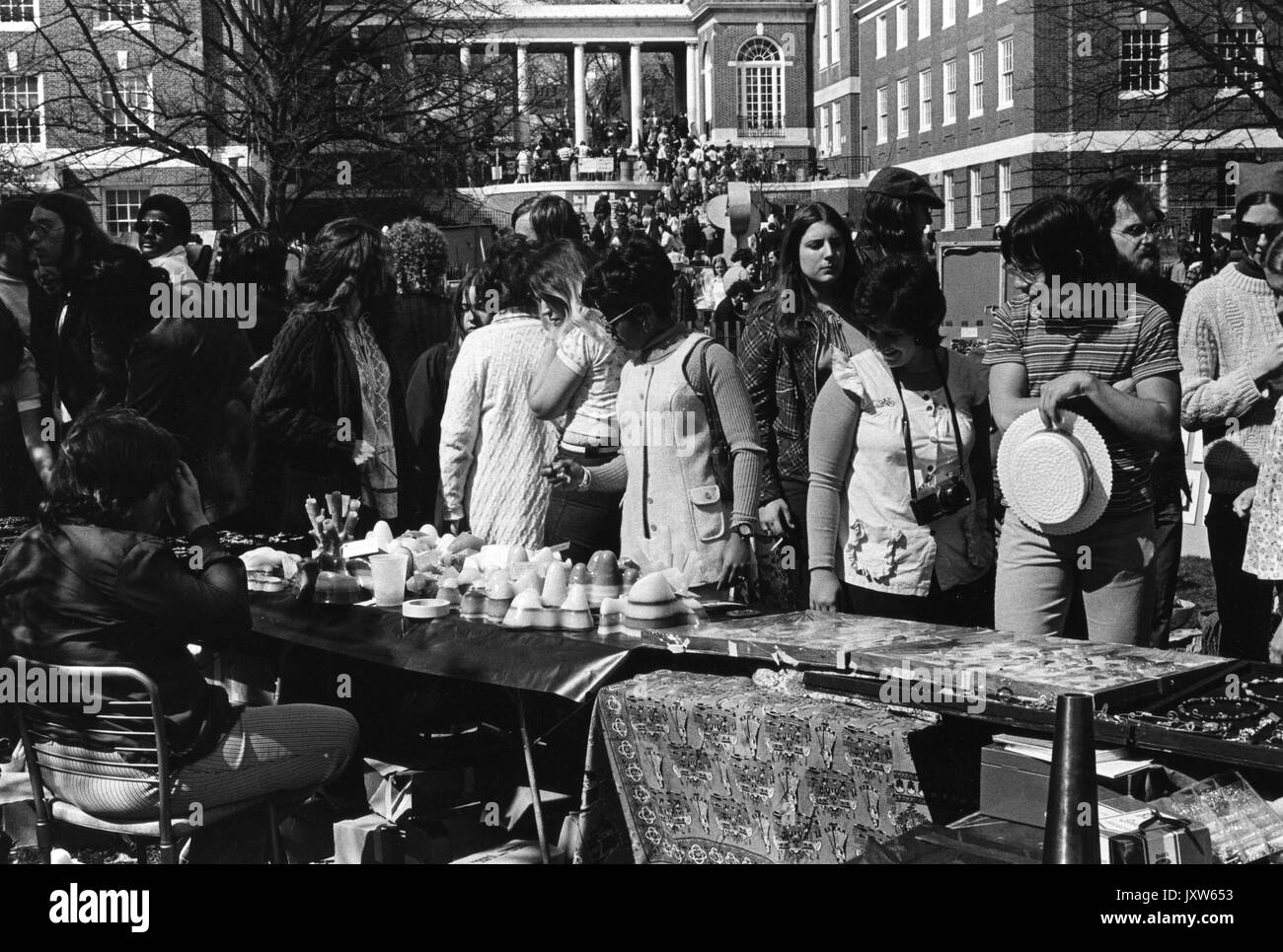 Students looking at vendors wares at Spring Fair, a Spring carnival, outdoors, vendor tents and a large crowd in the background, at Johns Hopkins University, 1972. Stock Photo