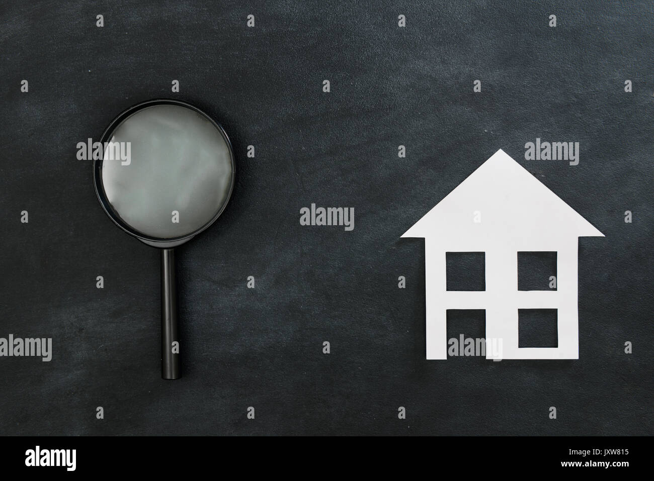 high angle view photo of magnifier with paper house on black chalkboard ...
