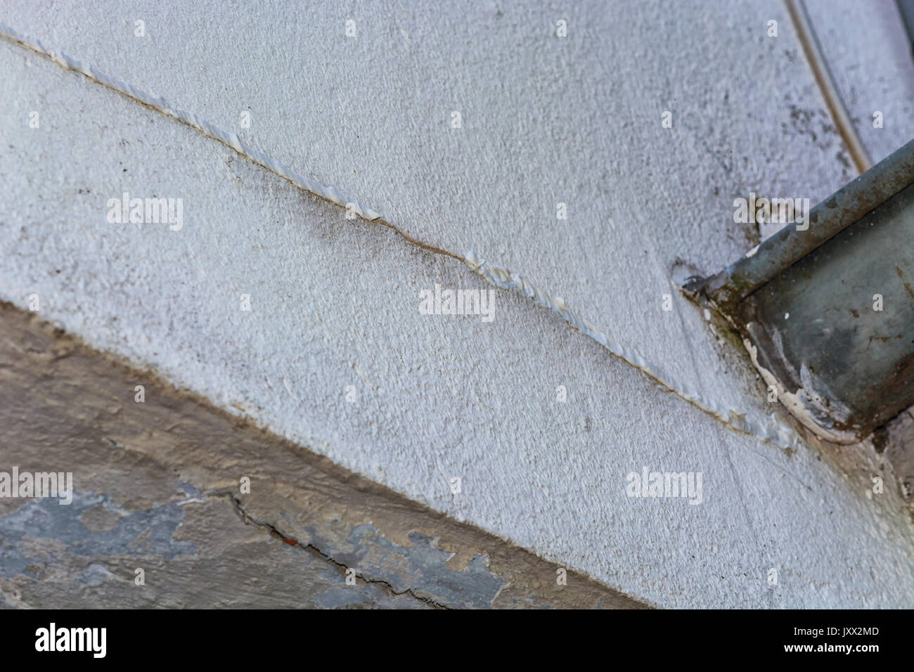 Small cracks in the plaster on the outer wall of the caused by a structural damage. Stock Photo