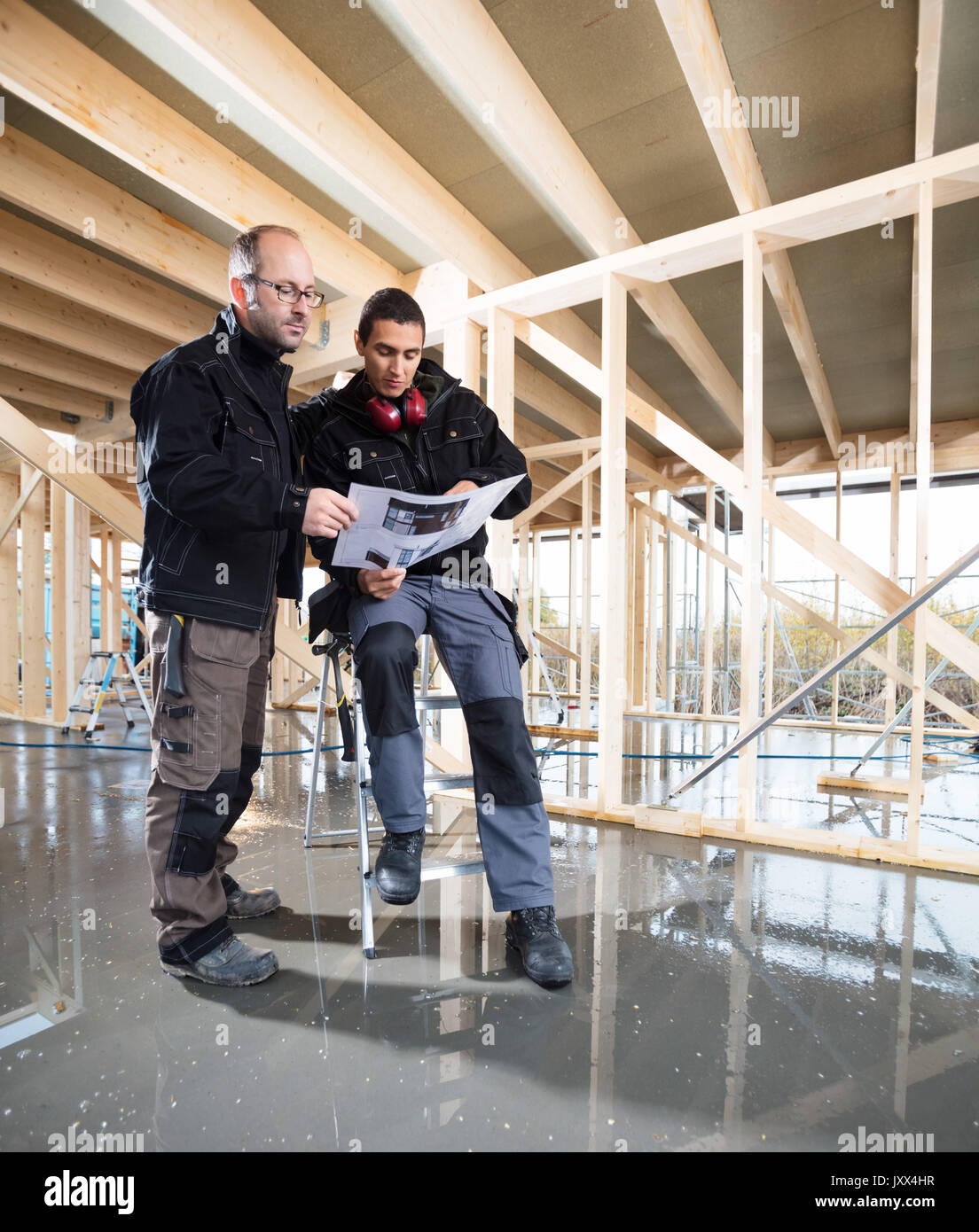 Full Length Of Carpenters With Plan At Construction Site Stock Photo