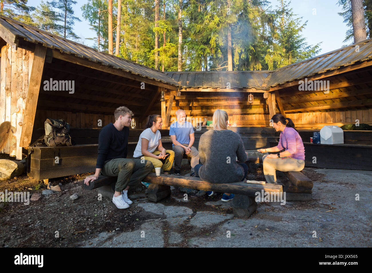 Friends Cooking Food By Shed In Forest Stock Photo