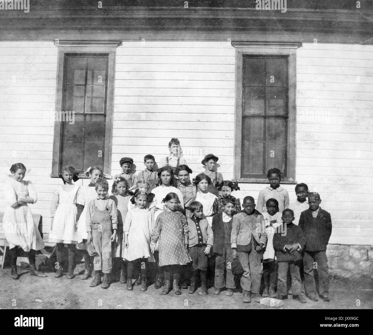 Full length landscape shot of schoolchildren outdoors, six African American students in the cluster on the right, 1912. Stock Photo