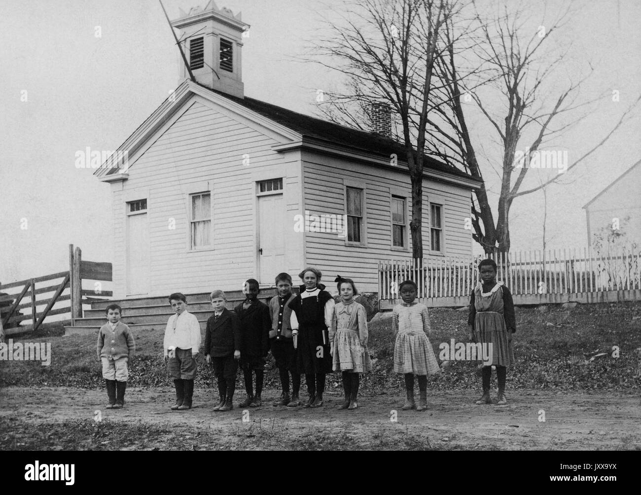 Full length landscape shot of nine students standing outside schoolhouse, three African American students, 1920. Stock Photo