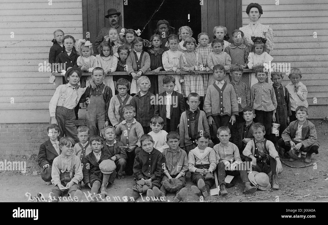 Full length landscape shot of schoolchildren seated and standing outdoors, African American students 'in last row as usual', 1920. Stock Photo