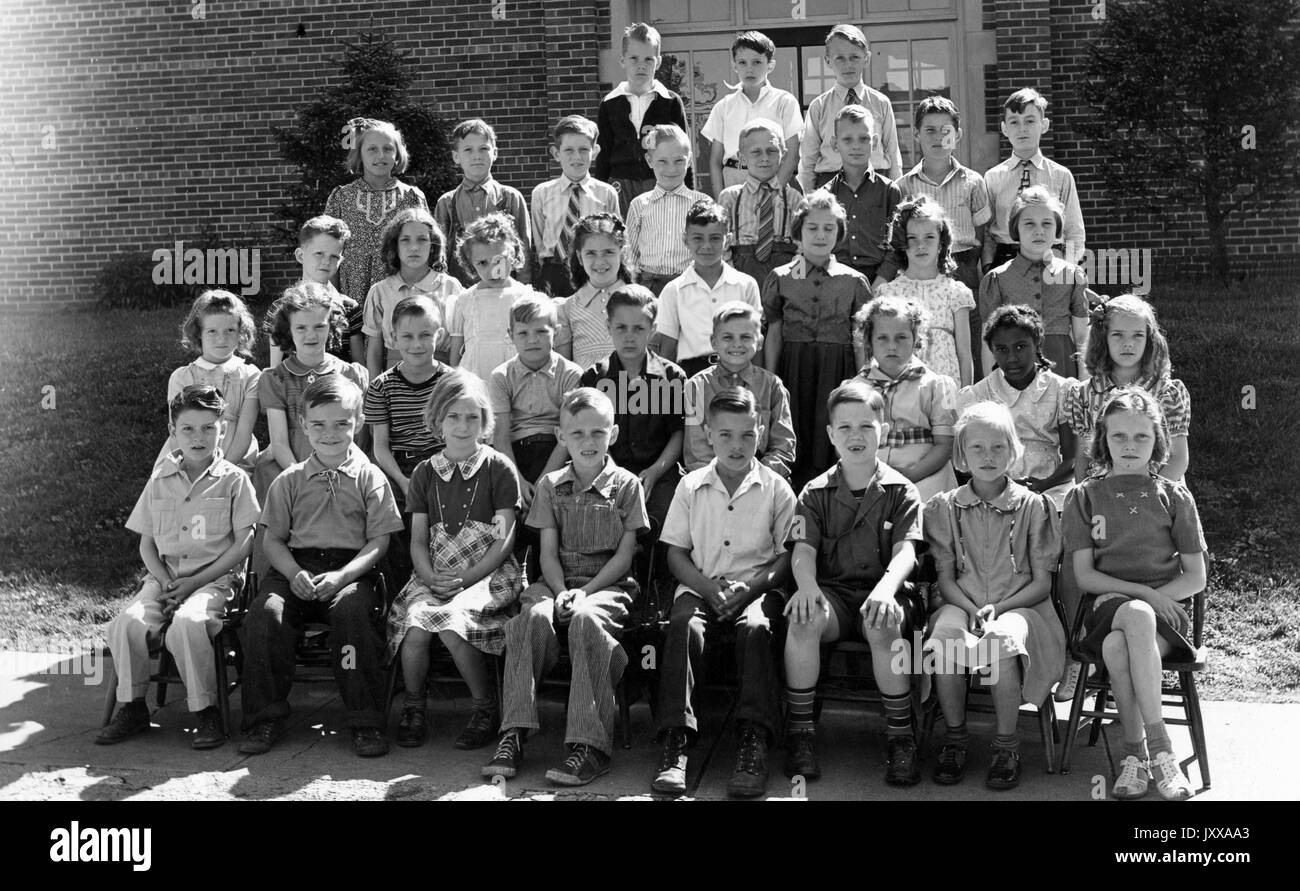 Full length landscape shot of schoolchildren, seated, one African American girl in the second row, 1920. Stock Photo