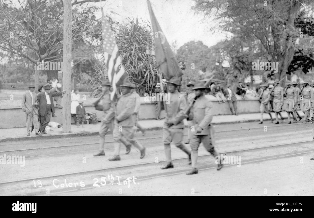 African American soldiers who are part of the 25th Infantry Division of the United States Army located in Hawaii are walking in a parade and holding the American flag and an unidentified flag, 1941. Stock Photo