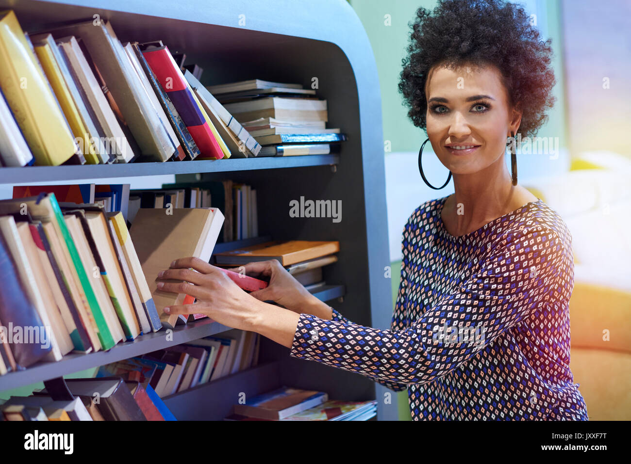 Woman kneeling next to the bookshelf Stock Photo