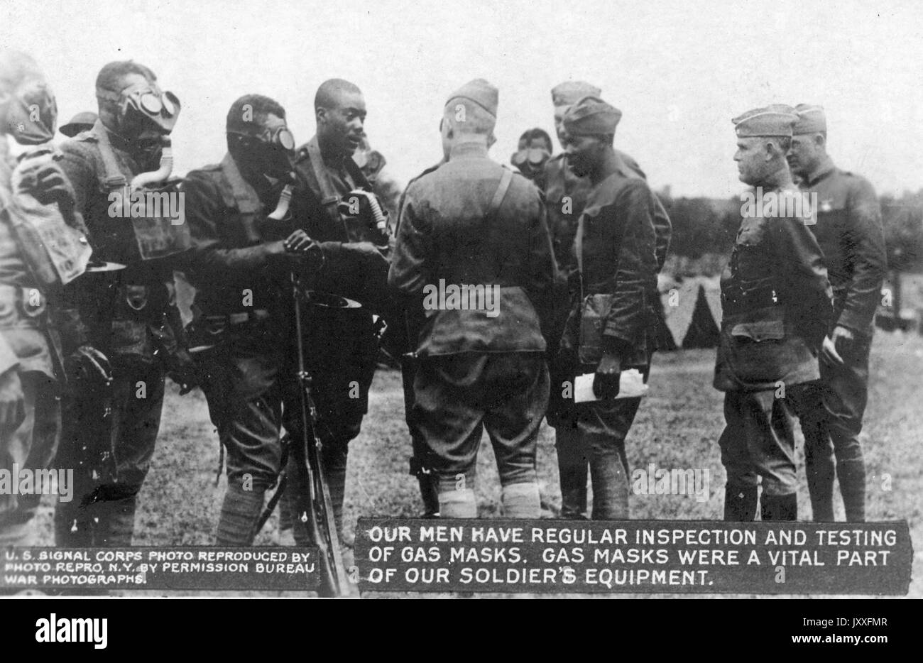 World War I US Signal Corps having regular inspection and testing of gas masks; African American soldiers standing around higher ranked officers wearing gas masks, 1917. Stock Photo