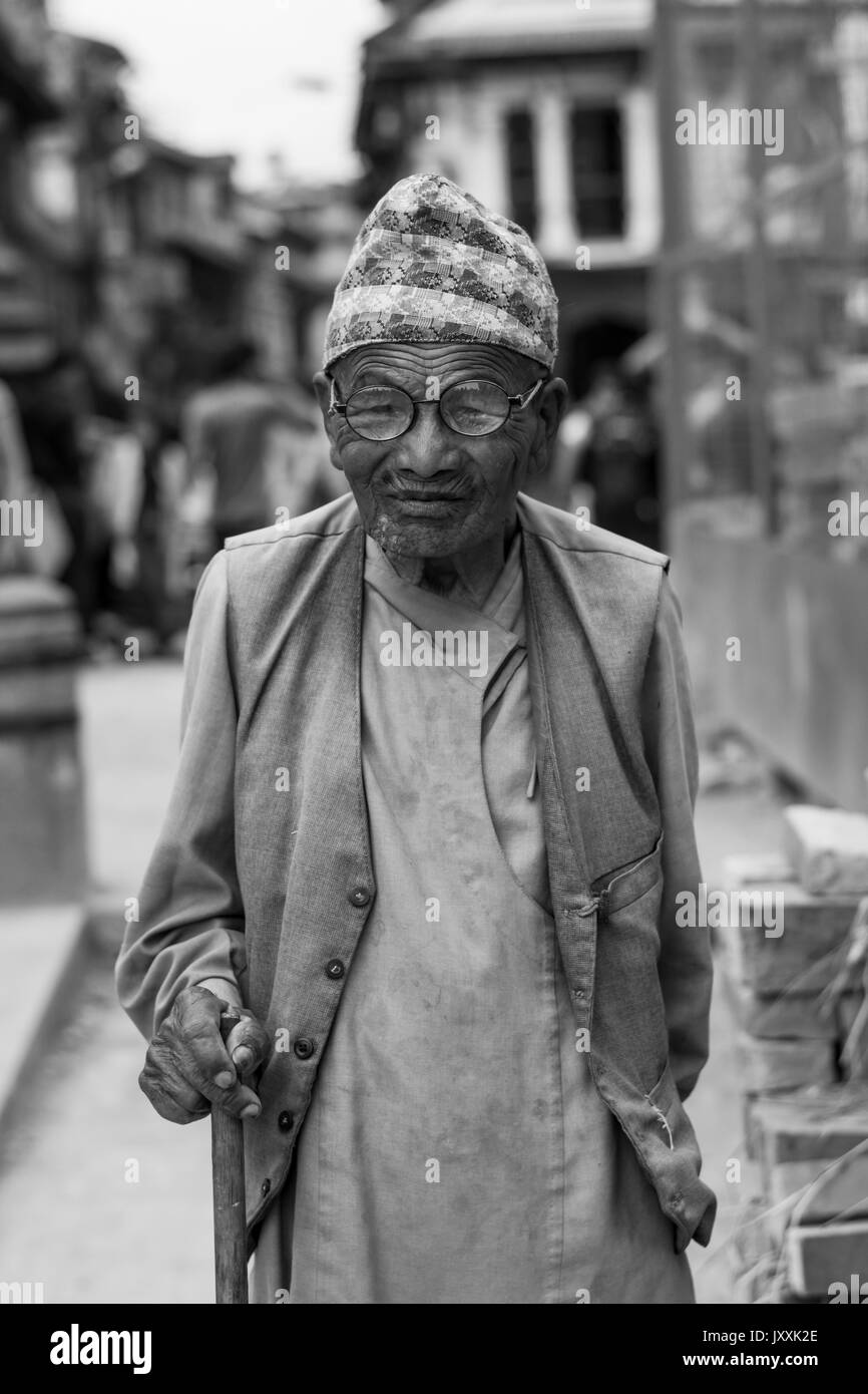 14 June 2017 : protrait of unknown old man wearing traditional Nepali dress with spectacles and holding stave smiling to camera Stock Photo