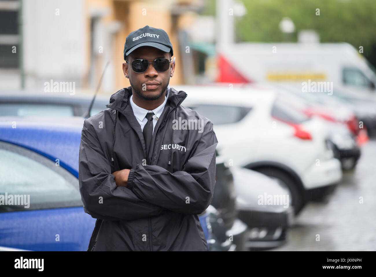 Portrait Of Young African Male Security Guard In Uniform Standing Arms Crossed On Street Stock Photo