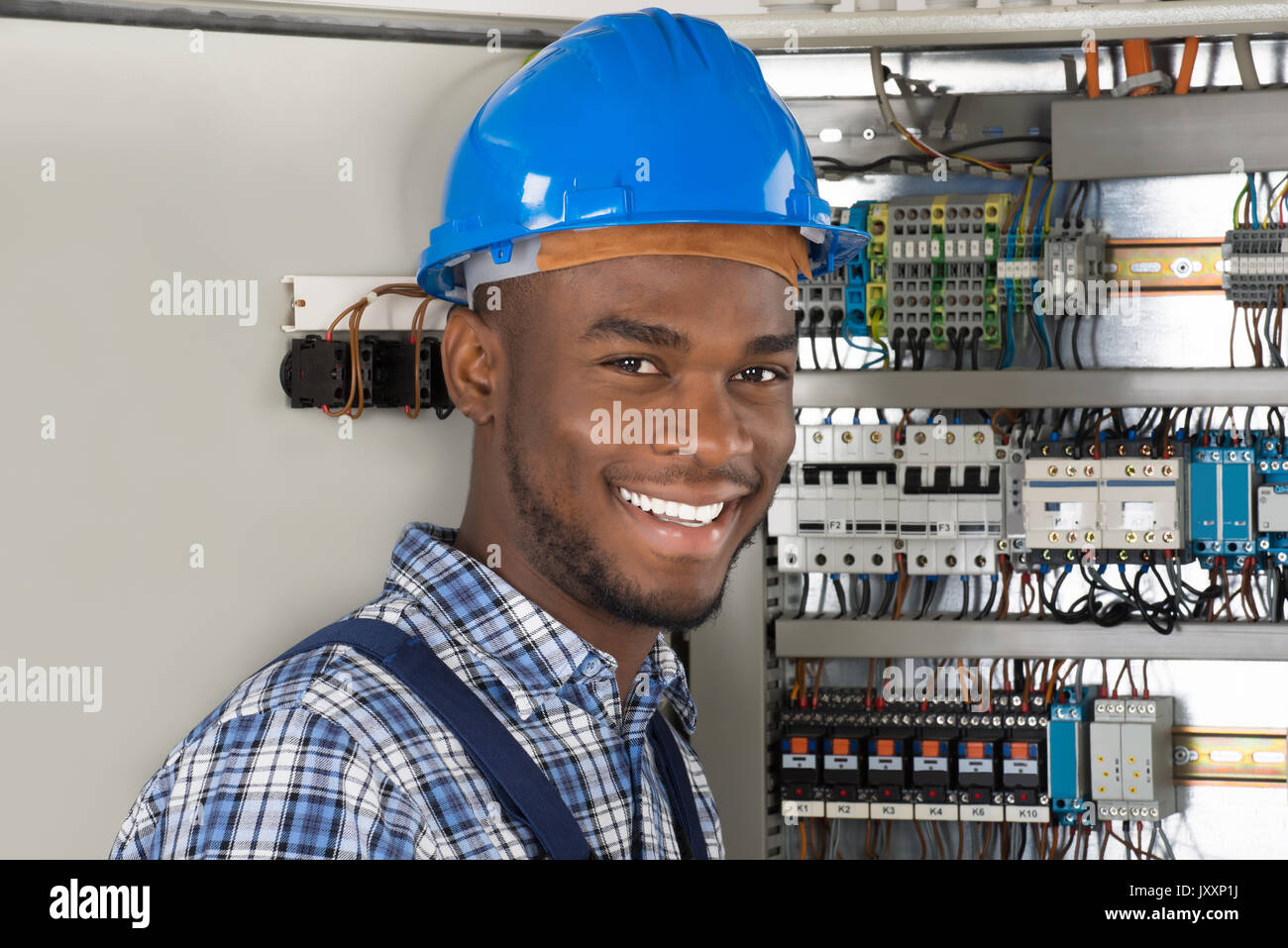 Male Technician Holding Clipboard While Examining Fusebox Stock Photo