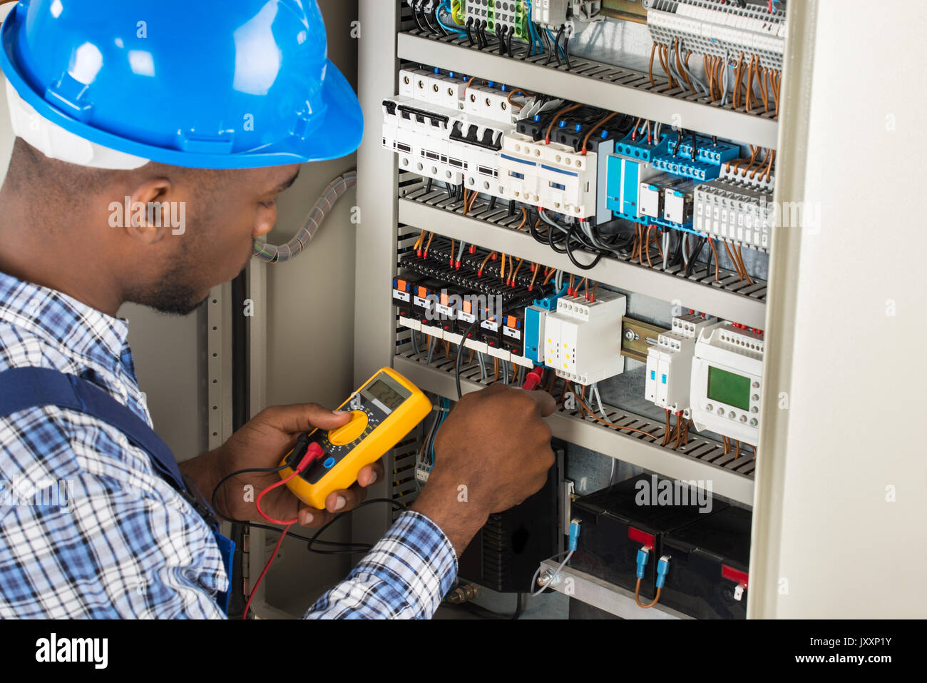 Close-up Of Male Electrician Checking Fuse Box With Multimeter Stock Photo