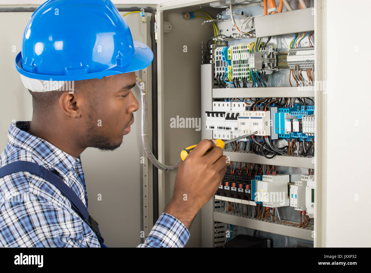 Close-up Of Young Male Technician Examining Fusebox With Screwdriver Stock Photo