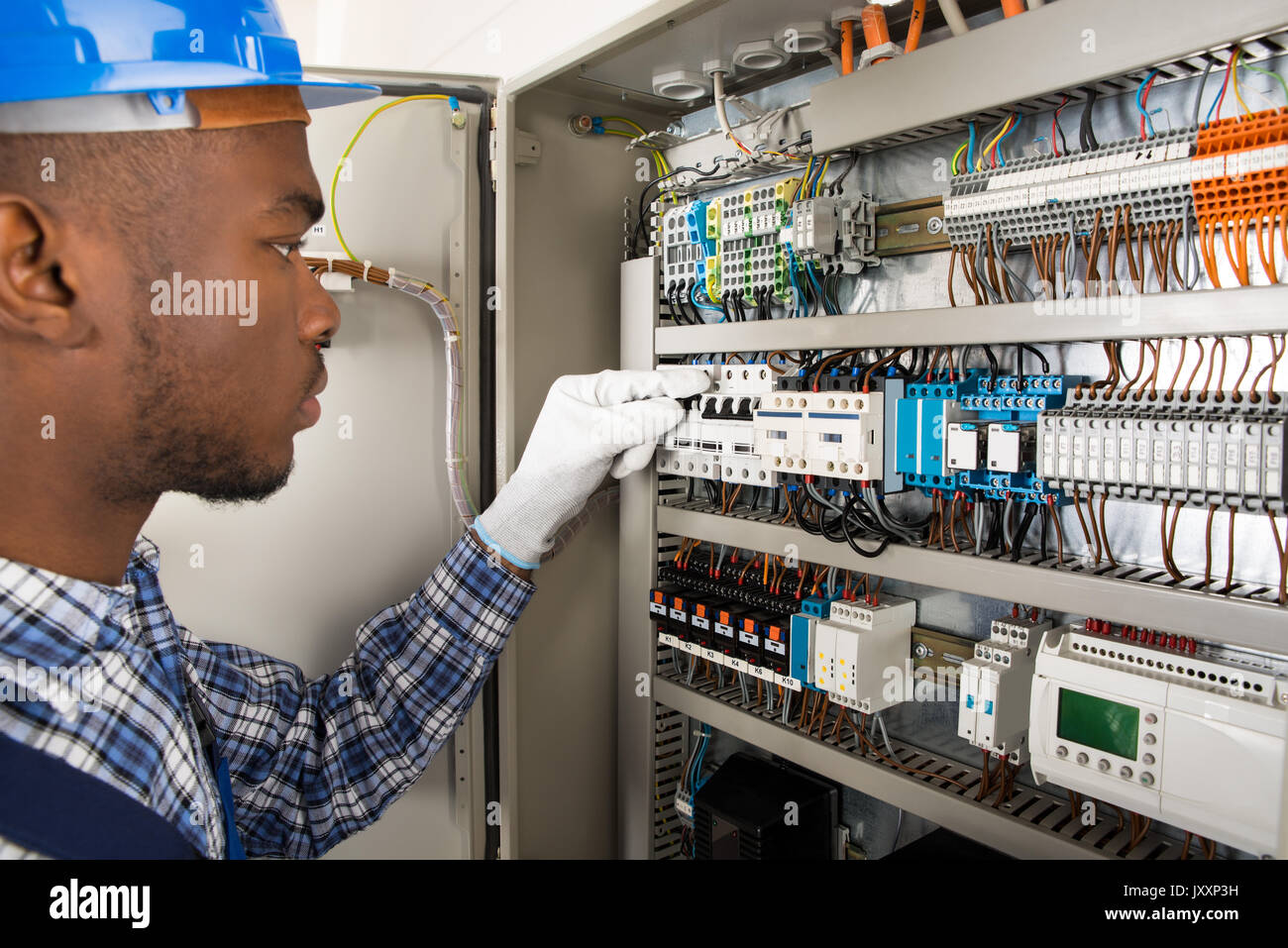 Photo Of Young African Male Technician Checking Fusebox Stock Photo