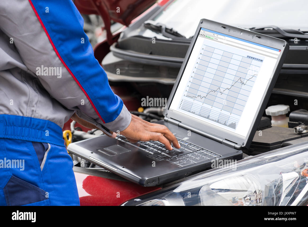 Close-up Of Male Mechanic Using Laptop For Examining Car Engine Stock Photo