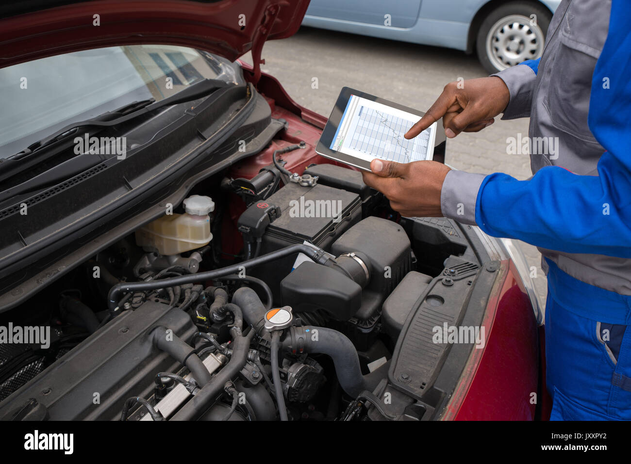 Close-up Of Mechanic With Digital Tablet Showing Graph While Examining Car Stock Photo