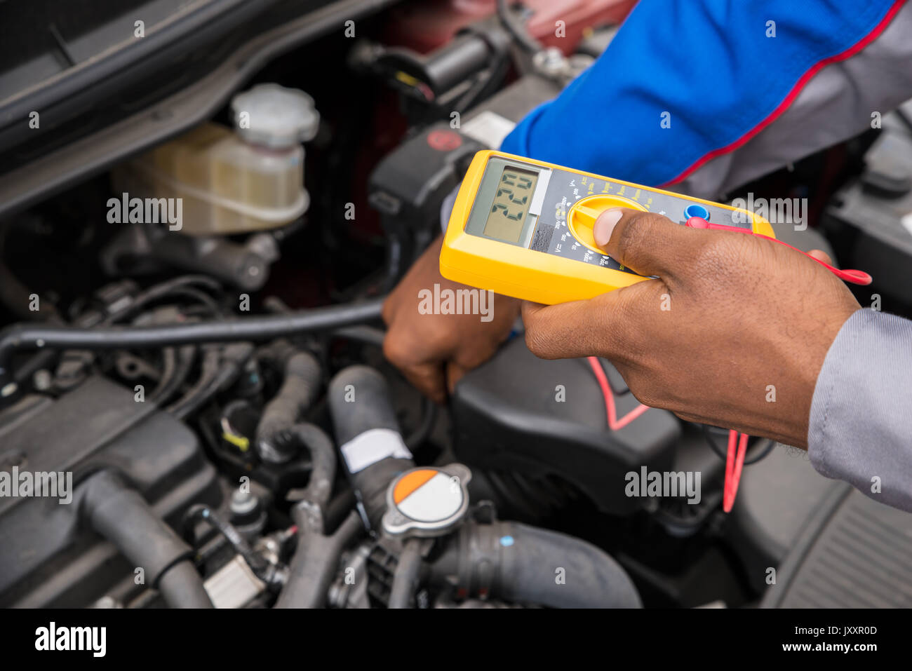 Close-up Of Mechanic Checking A Car Battery Level With Multimeter Stock Photo