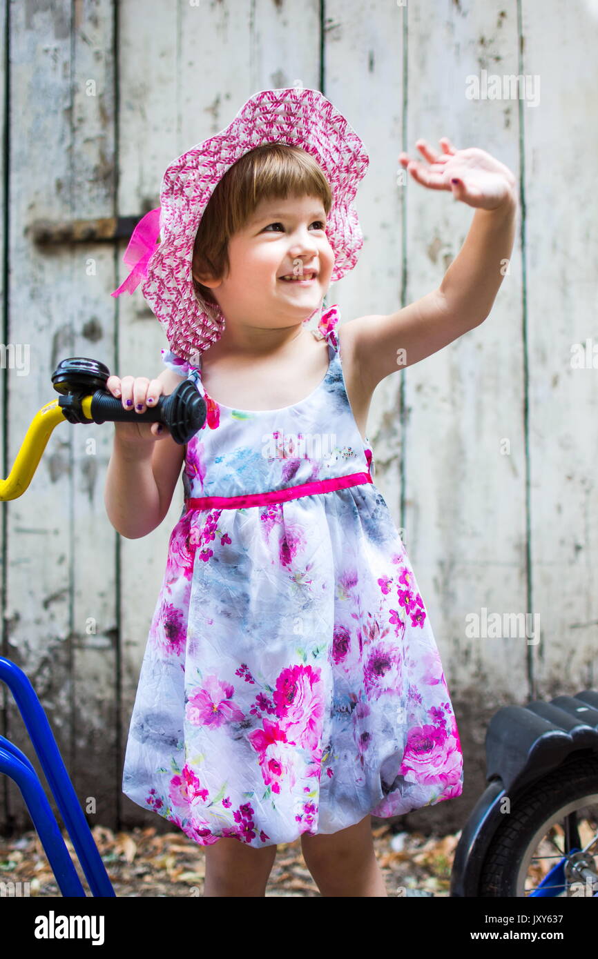 Three years old girl sending regards with a bicycle outdoors Stock Photo