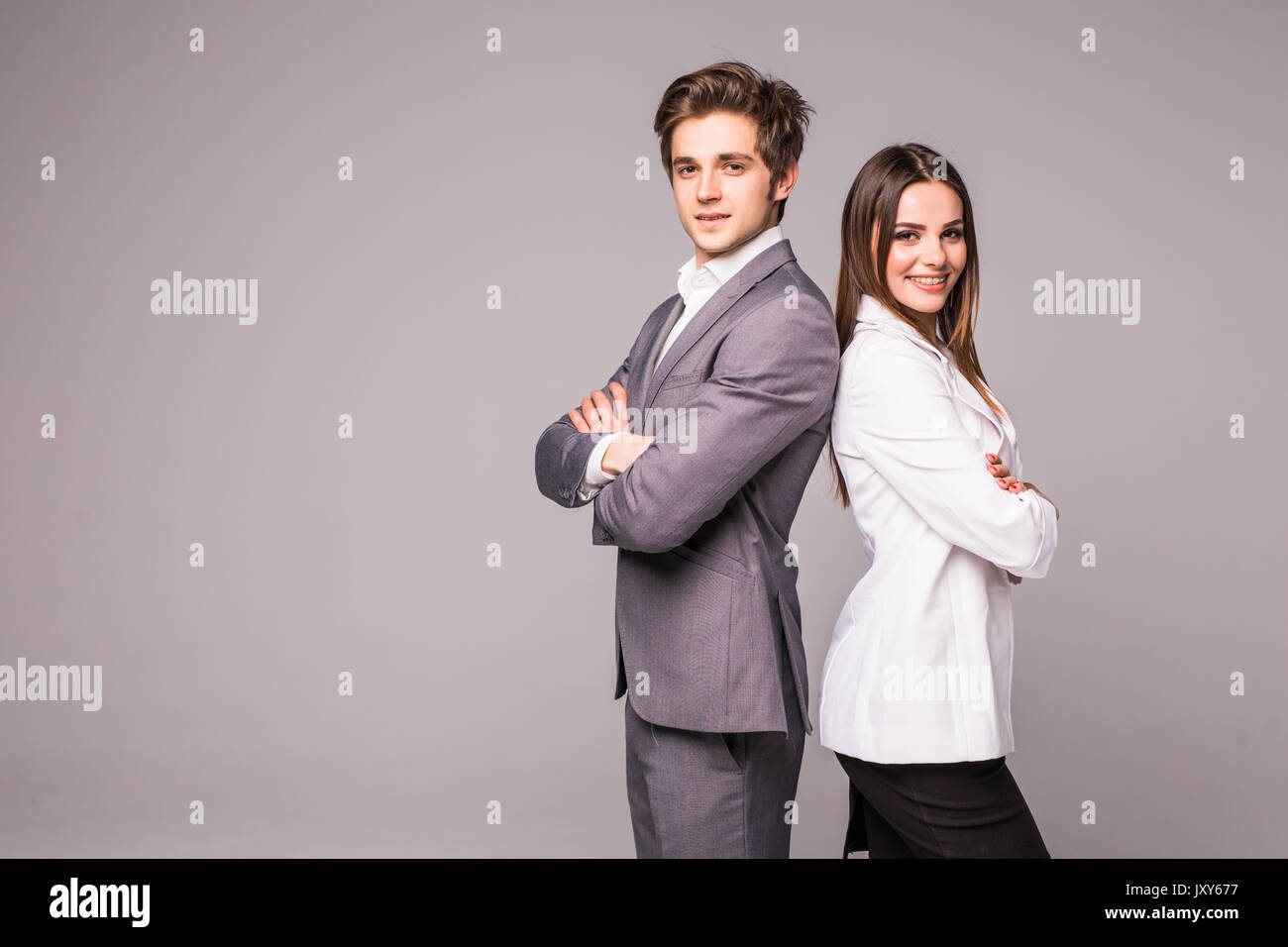 Two young business people standing back to back with hands crossed ...