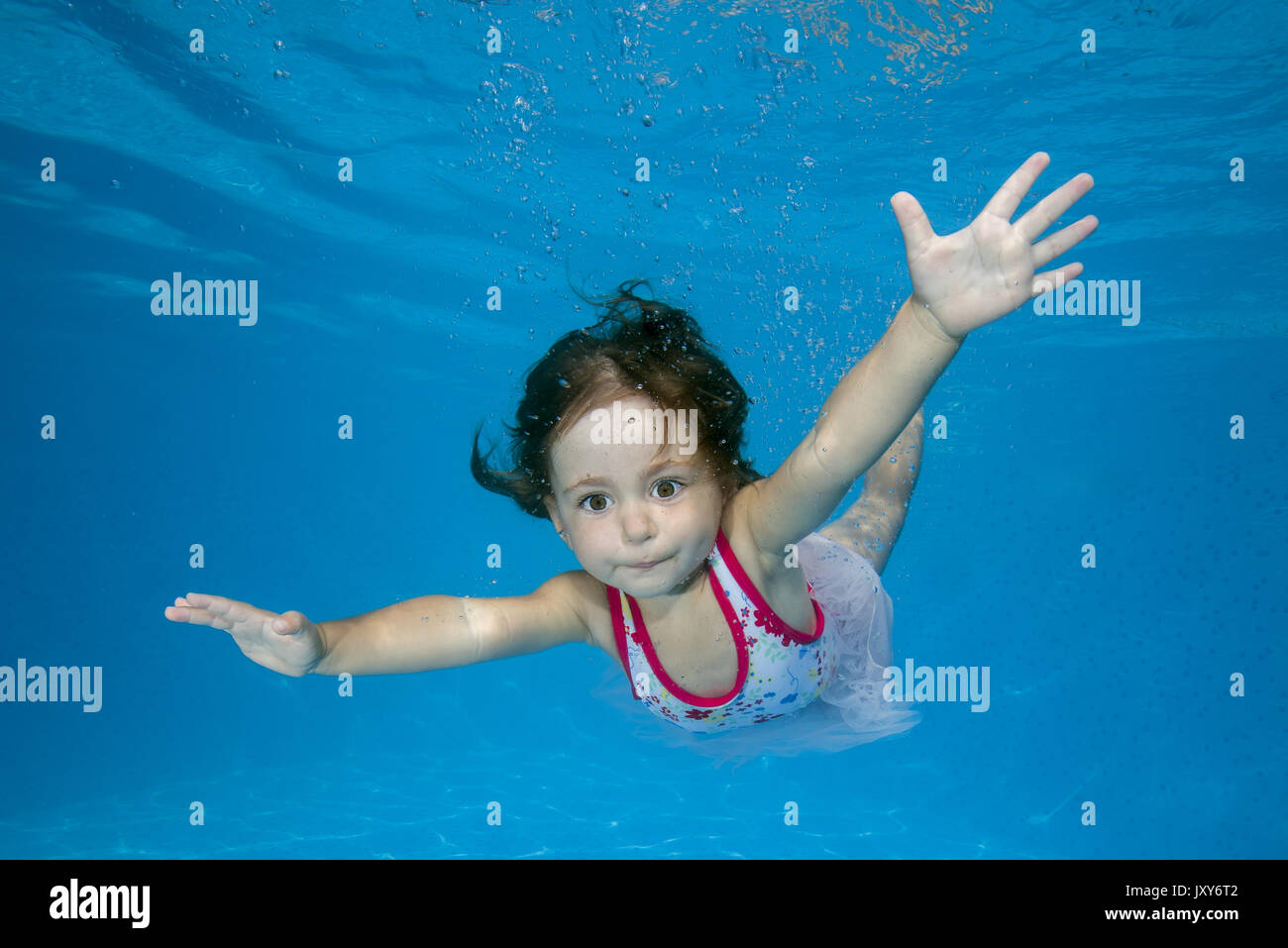 little girl learns to swim underwater in the pool Stock Photo