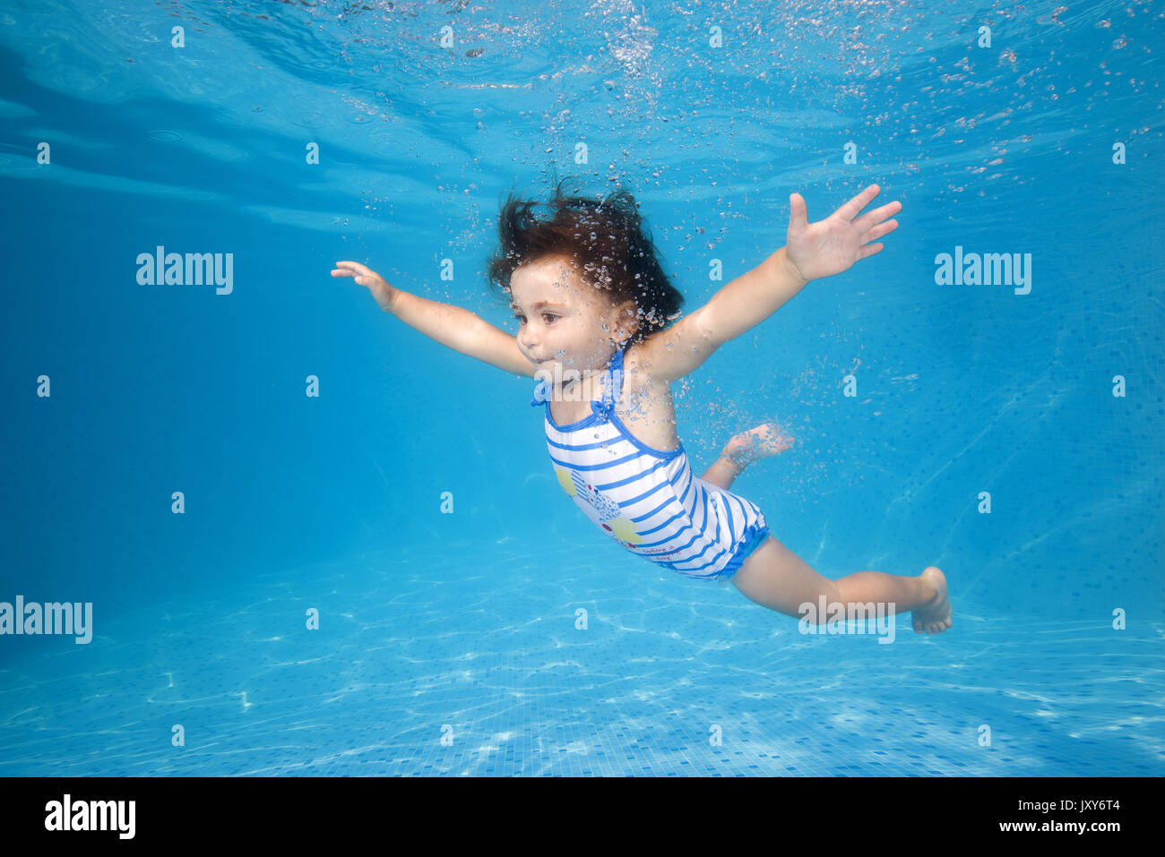 little girl learns to swim underwater in the pool Stock Photo
