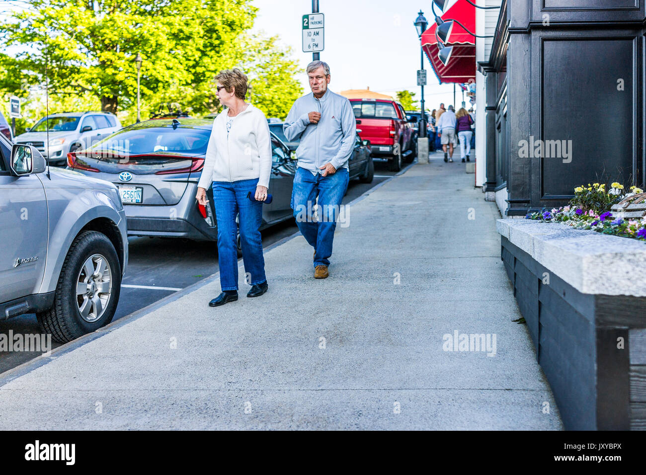 Bar Harbor, USA - June 8, 2017: Older couple walking on sidewalk during sunset in downtown village in summer Stock Photo