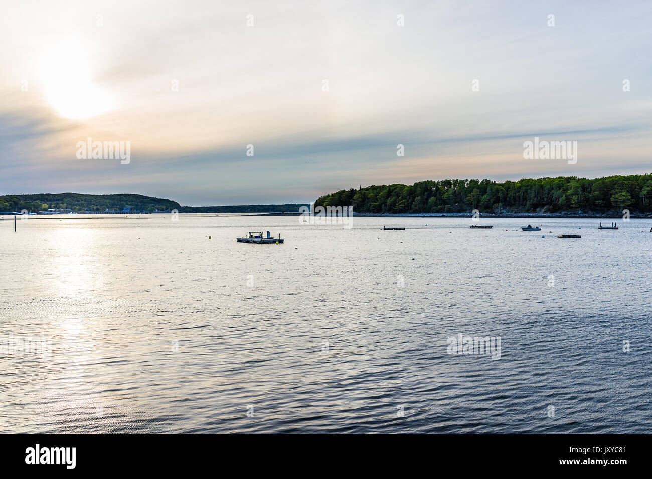 Sunset sun path in Bar Harbor, Maine village with empty boats in water Stock Photo