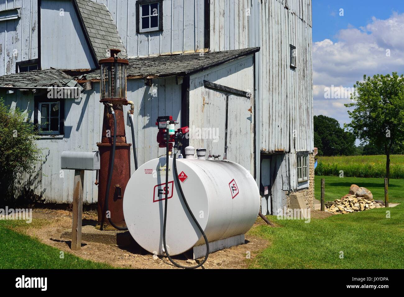 Vintage pump sits between a mailbox and current day propane tank on farm in northeastern Illinois, USA. Stock Photo