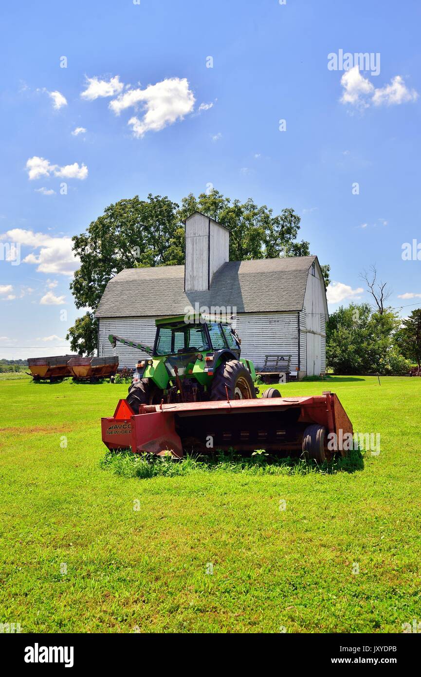Veteran tractor and equipment in front of a venerable barn on a farm in northeastern Illinois. Stock Photo