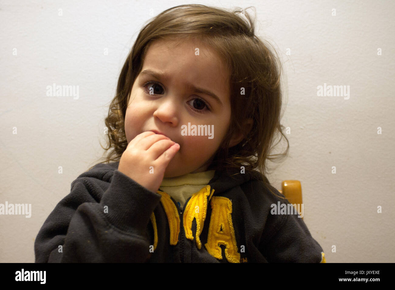 Young girl with a quizzical expression touches her mouth Stock Photo