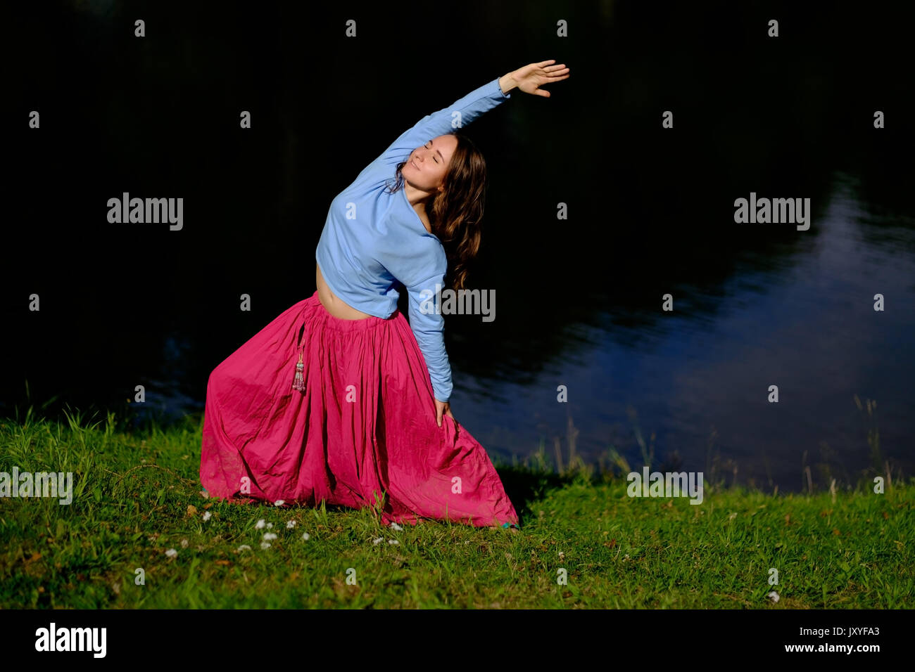 Sporty fit caucasian woman doing asana Virabhadrasana 2 Warrior pose posture in nature. Stock Photo