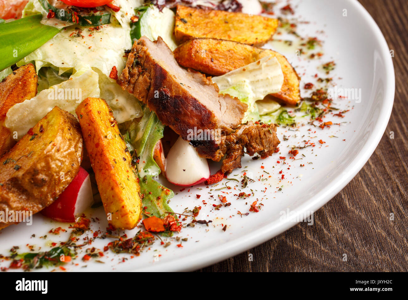 restaurant meals, delicious food, fried foods - salad with fresh vegetables grilled veal and baked potatoes on the plate on a wooden table. Stock Photo