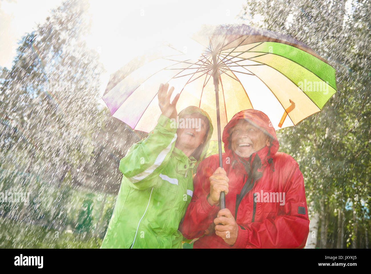 Happy couple standing with umbrella Stock Photo - Alamy