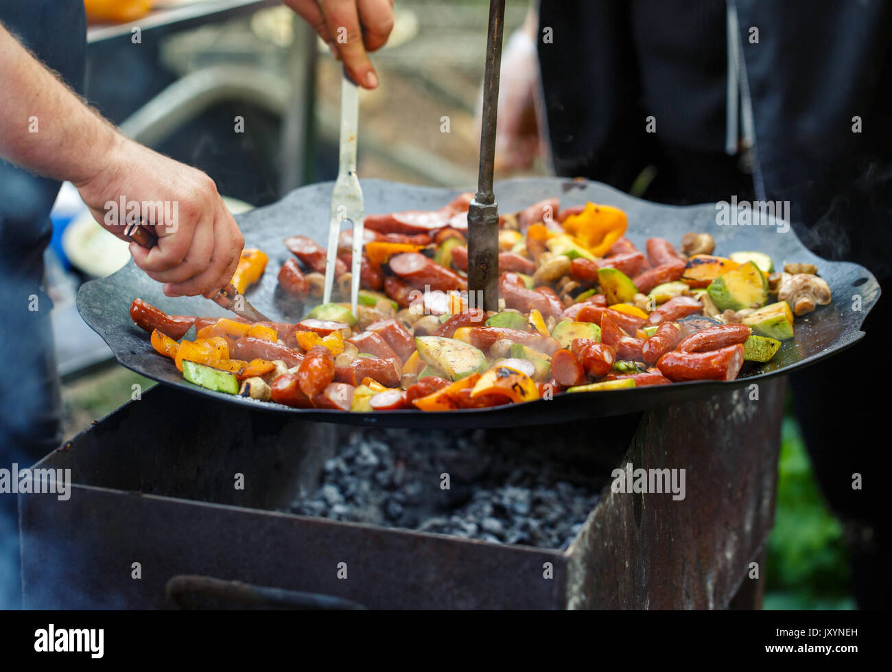 hiking, cooking in the forest and outdoor activities concept - active recreation, sausage, mushrooms and grilled vegetables on the grill Stock Photo