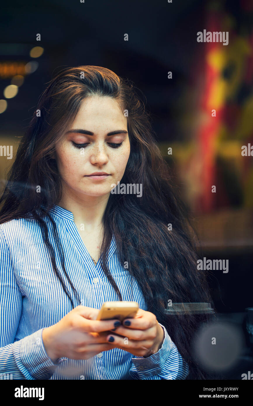 Serious Caucasian woman texting on cell phone Stock Photo