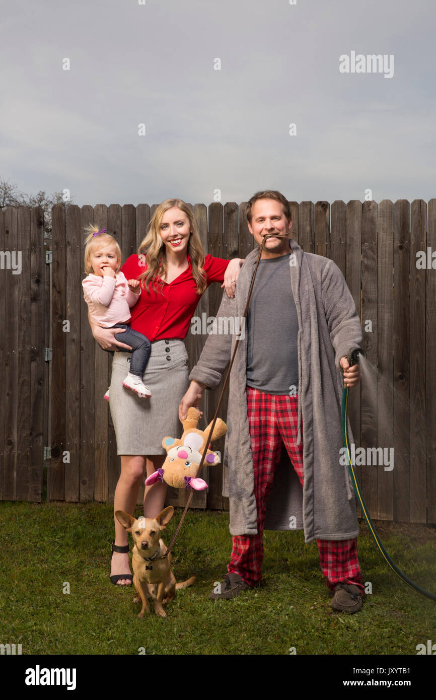 Caucasian couple posing near wooden fence with baby daughter Stock Photo