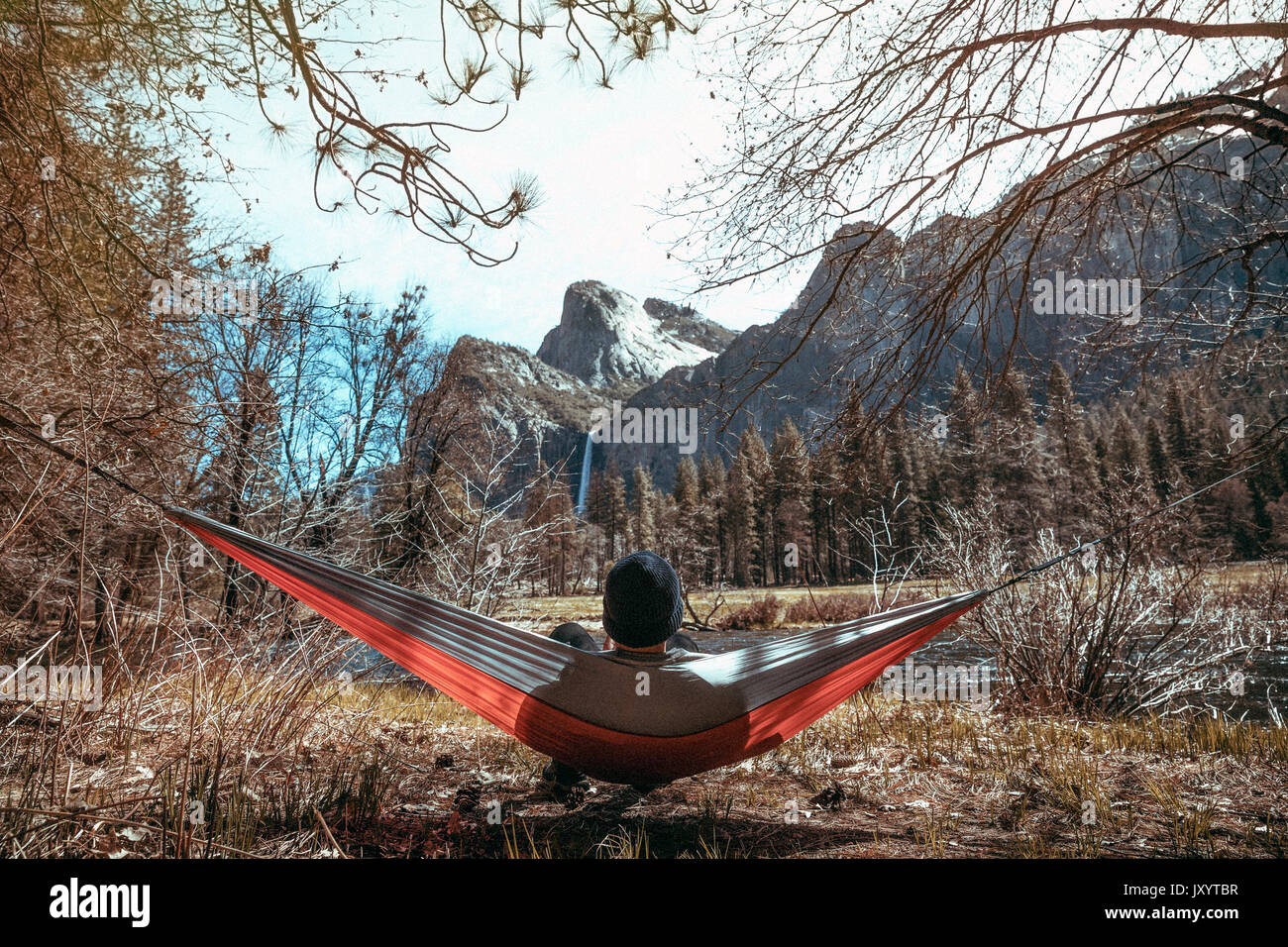 Caucasian man laying in hammock near mountains Stock Photo