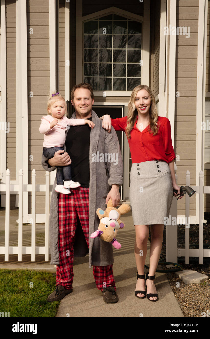 Caucasian couple posing near house with baby daughter Stock Photo