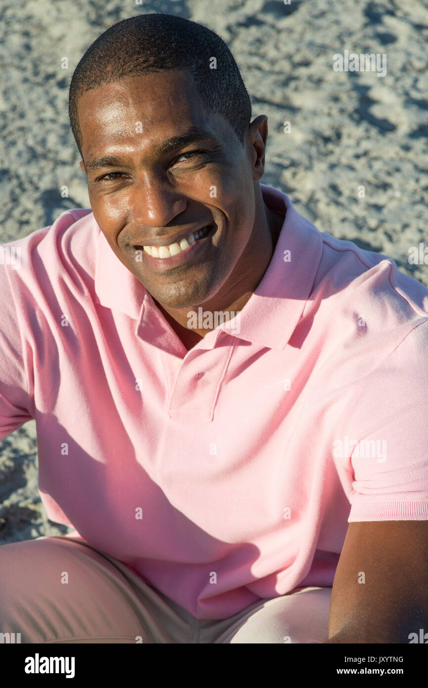 Portrait of smiling Black man sitting on beach Stock Photo