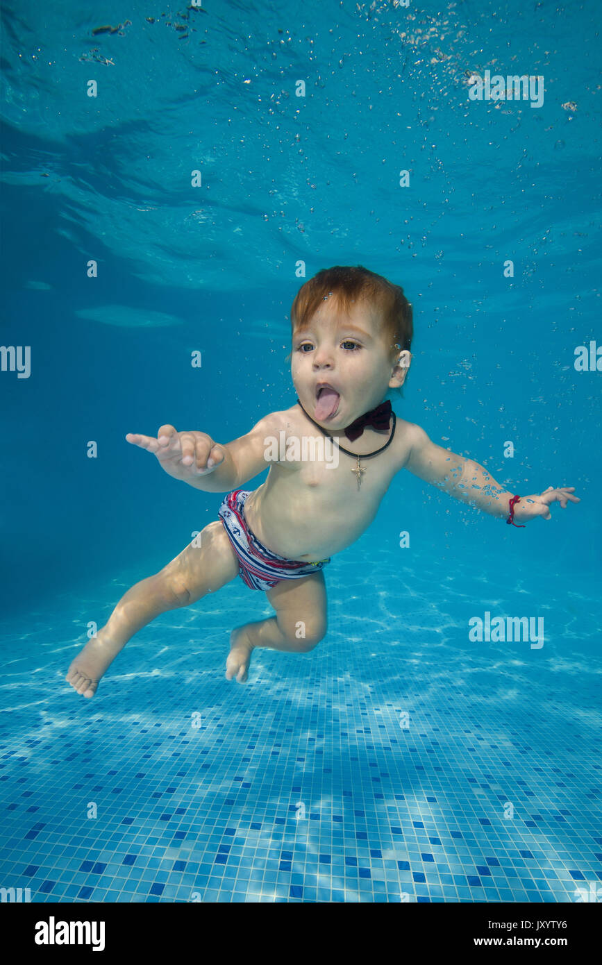8 months boy learning to swim in the pool 2. AMUSING shots show the exhilarated and confused faces water babies can pull when dunked into swimming poo Stock Photo