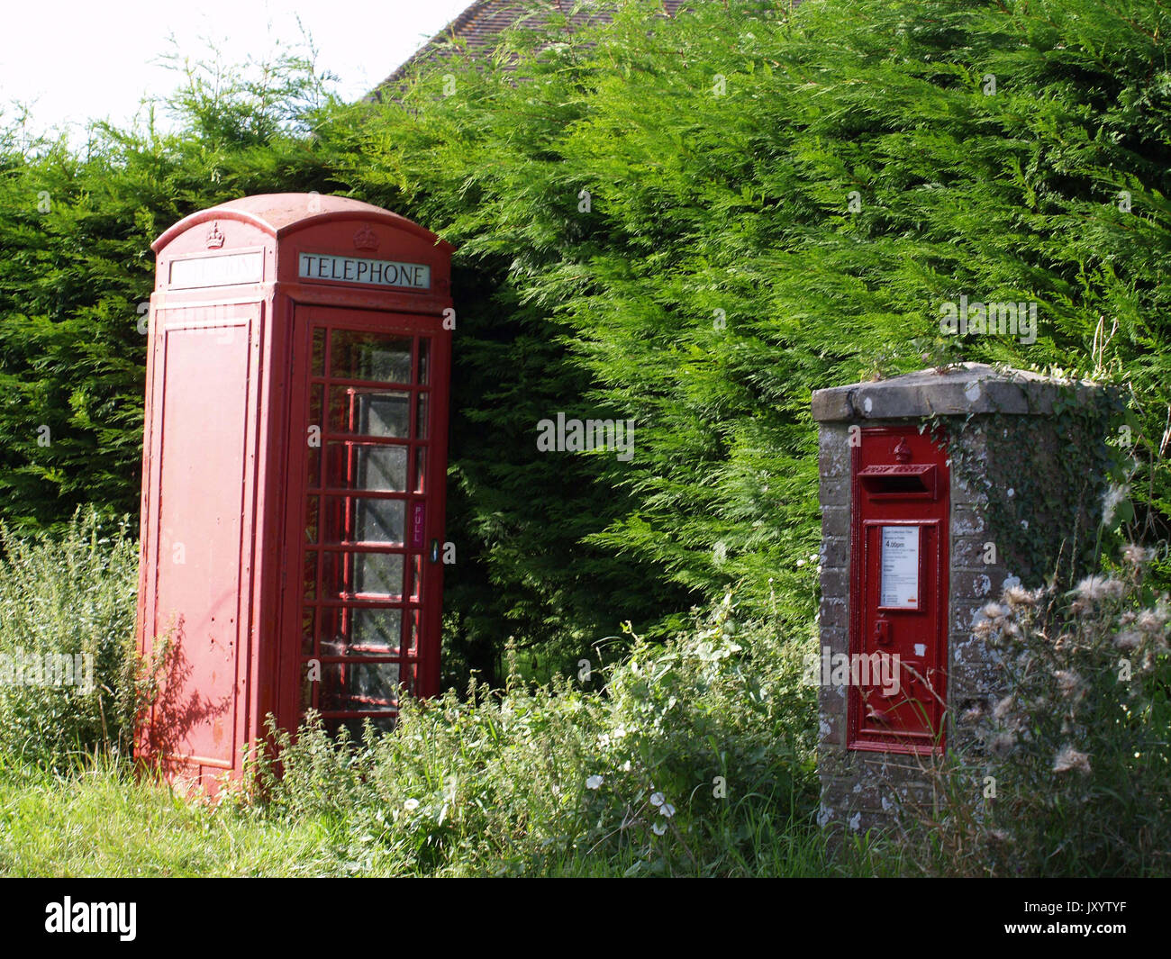 Traditional red telephone and post box on English country lane near