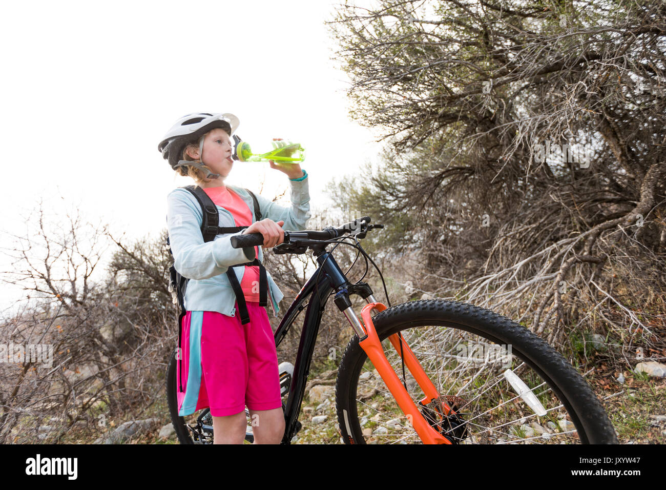Caucasian girl holding bicycle and drinking water Stock Photo