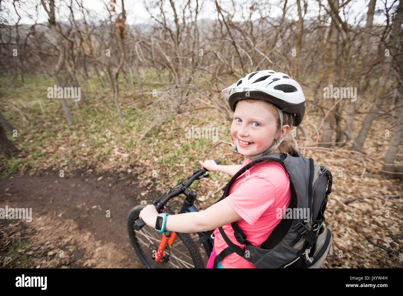 Caucasian girl riding bicycle on forest path Stock Photo