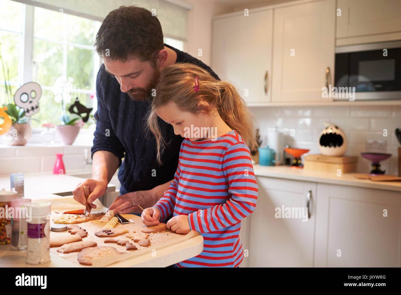 Father And Daughter Baking Halloween Cookies Together Stock Photo